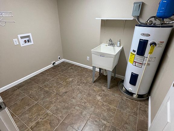 Utility room with washer and dryer hookup note the mud sink and storage shelves on the left for handing clothes