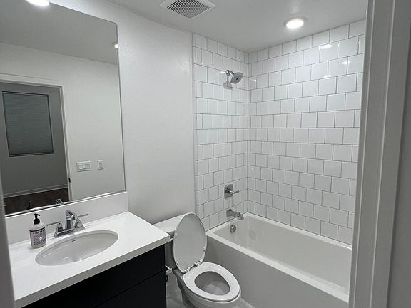 Bathroom with LED surface mount lights, white quartz countertop, tiled bathtub to ceiling. All brand new.