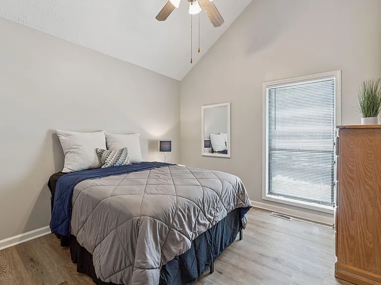 Room with vaulted ceilings, mirror, dresser, ceiling fan.