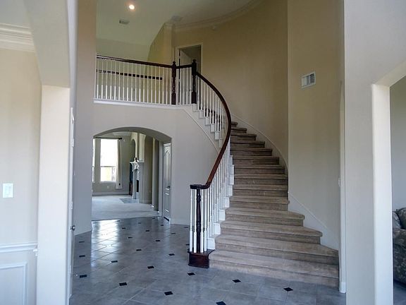 The wide open foyer has a two-story high ceiling and a beautiful curved staircase.