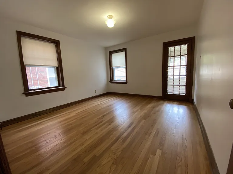 Bedroom with hardwood floors and window coverings.