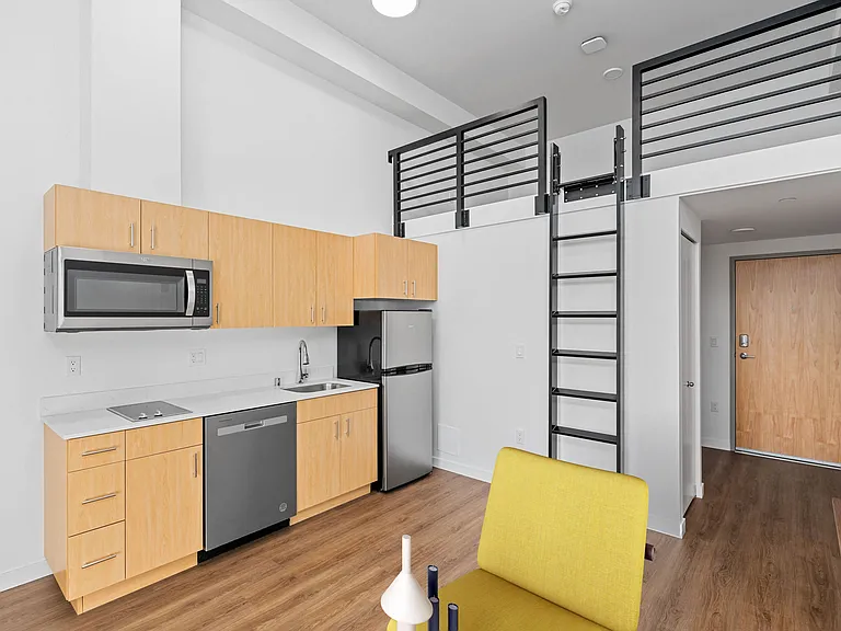 This compact apartment features a kitchen area and a loft bed, maximizing space for efficient and comfortable living.