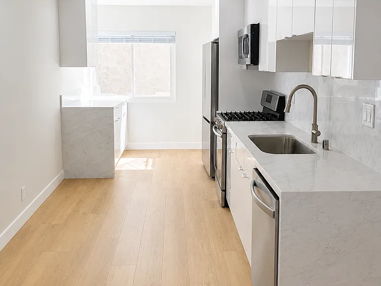 Updated kitchen with glossy white cabinetry, stainless steel appliances, marble-look counters, and full-height backsplash