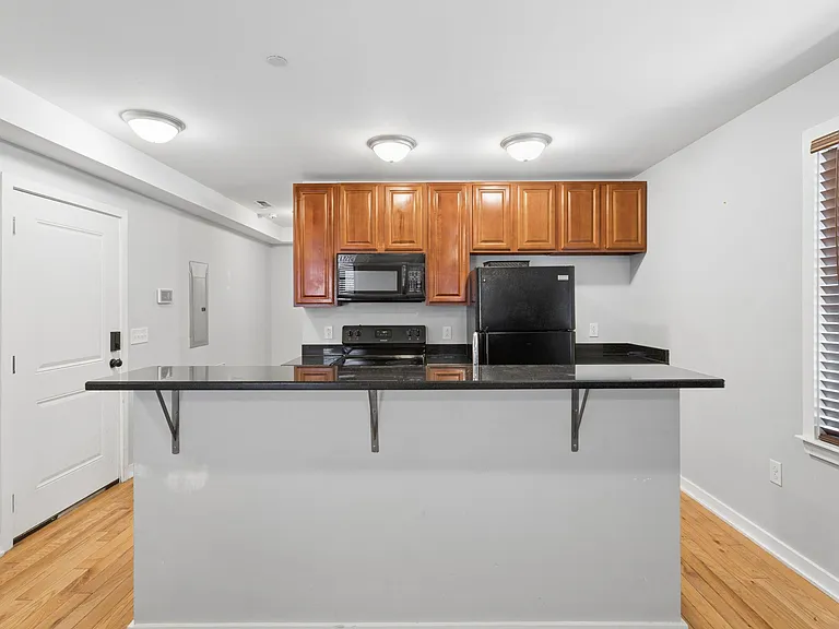 Eat-in kitchen with breakfast bar, ample upper cabinetry, and full appliance set including range and microwave.