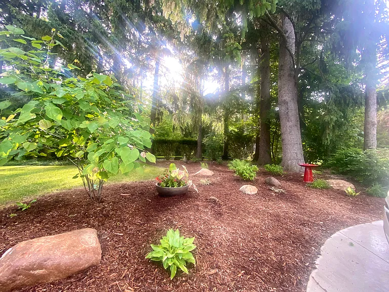 Enjoy a stunning, peaceful backyard filled with trees and charming birdhouses. Beyond the gate, you'll find a second outdoor space featuring Adirondack chairs and a horseshoe game, perfect for relaxation and fun.