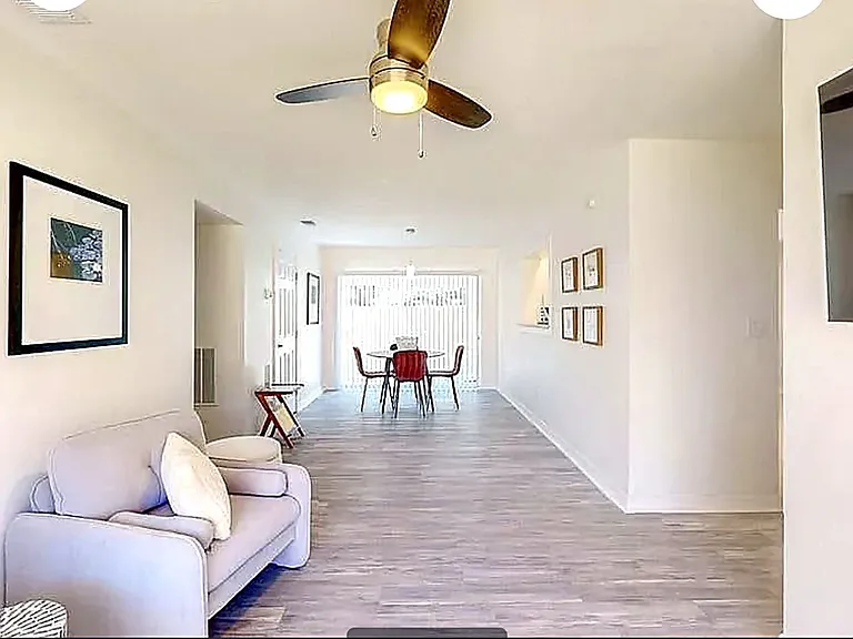 Spacious common area flowing from living room to dining space with backyard access via sliding glass door