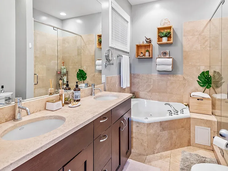 En suite bathroom with double sink, whirlpool bathtub, and separate shower.