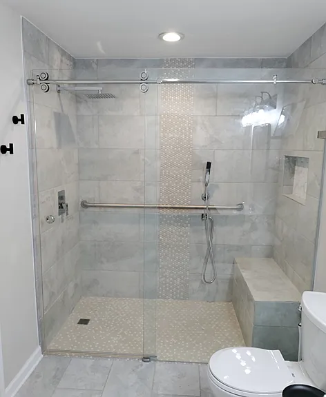 Large stepless standing shower with a rainfall showerhead, sprayer, and shower bench.