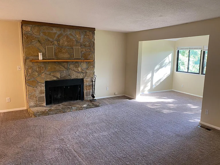 Living room with wood-burning fireplace and sunroom with vaulted ceilings.