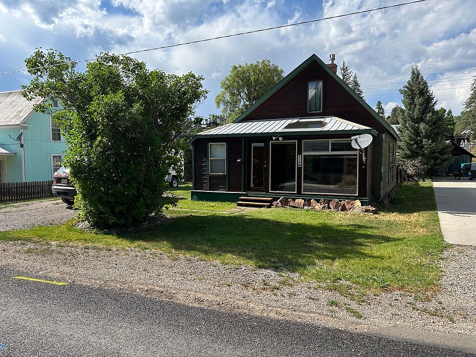 Front view of house from Hermosa Street. Lilac bush and one off street parking space in front yard. Three more parking spaces on left of house.