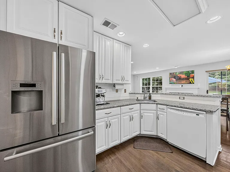 Bright Kitchen featuring granite counters, white cabinetry, stainless Bosch Appliances, open to the Family Room