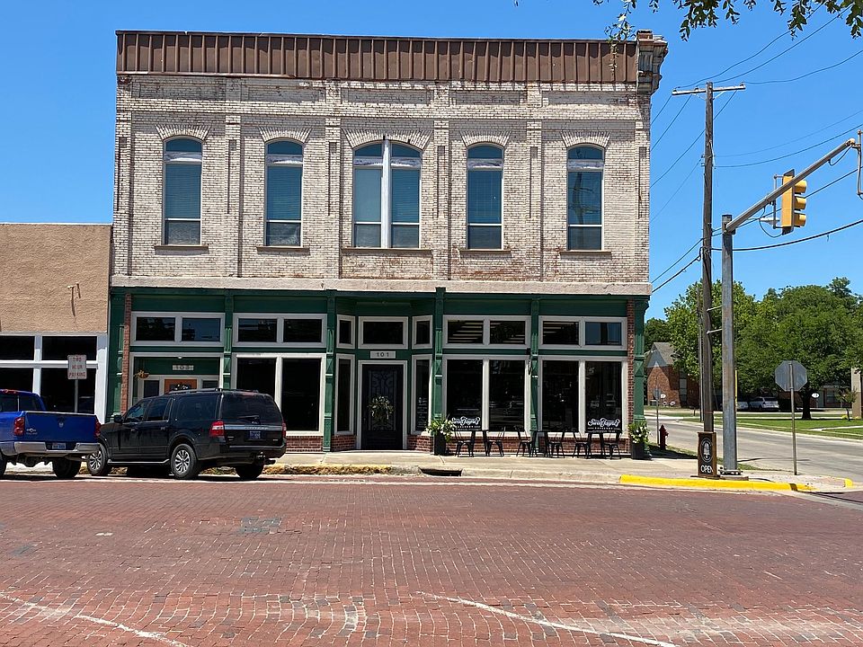 103 W. Broadway. Sweet Jane's Bakery is downstairs on the corner. Above the black vehicle you can barely see the Front Door that leads to the apartments. Back door leads to the parking lot.