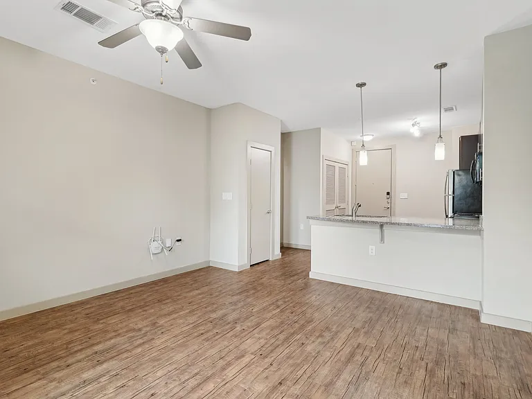 A room with a ceiling fan and wooden flooring.