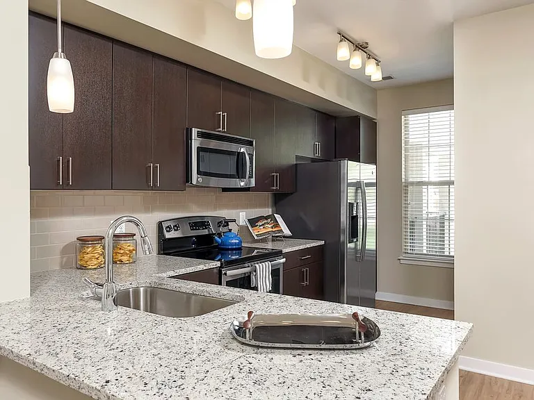 Classic Package II townhome kitchen with stainless steel appliances, espresso cabinetry, white speckled granite countertops, and hard surface flooring