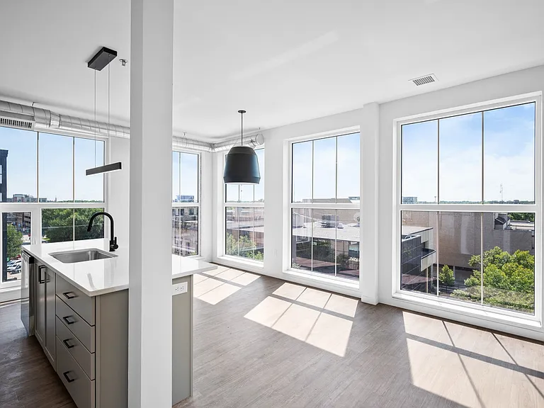 Bright, modern apartment with floor-to-ceiling windows, sleek kitchen island, and panoramic city views. Bright, modern apartment with floor-to-ceiling windows, sleek kitchen island, and panoramic city views.