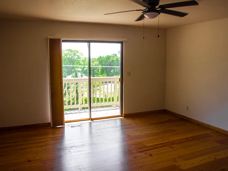 Primary bedroom with ensuite bathroom and large closet. View of yard and entrance to deck