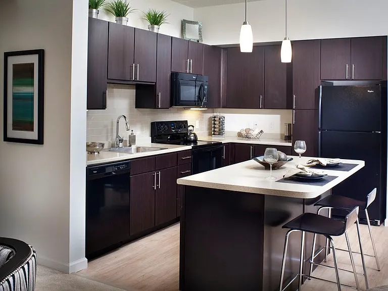 Classic Package kitchen with grey granite countertops, espresso cabinetry, stainless steel or black appliances, tile backsplash, and hard surface flooring (in select homes)