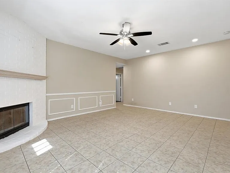 Unfurnished living room featuring ceiling fan, a fireplace, light tile patterned flooring, recessed lighting, and a decorative wall