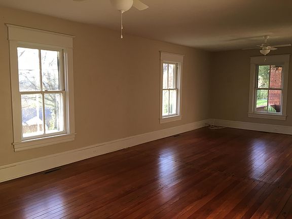 Living room view toward front porch and driveway. Front door (5 panel solid and original) not pictured, is to the right of end window. Also, note: the kitchen can be accessed by a door on each end of cottage.