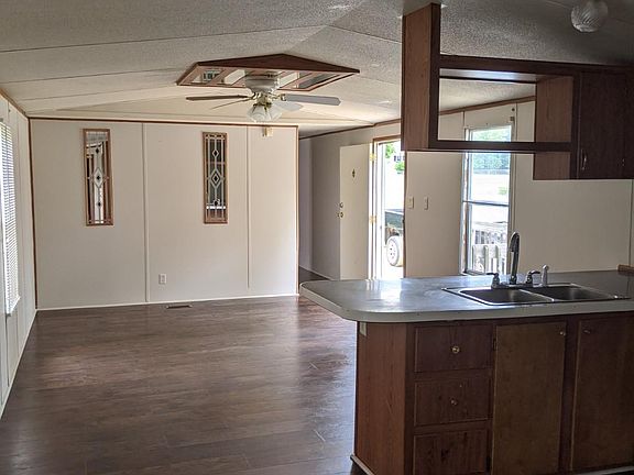 Open den to kitchen with faux wood floors, vaulted ceiling and ceiling fan.