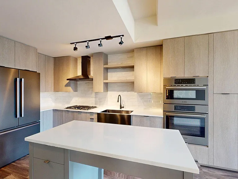 Apartment kitchen with stainless steel appliances and light counters.