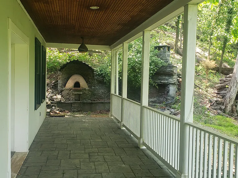 Main level back balcony off dining room showing pizza oven and wood-burning fireplace.