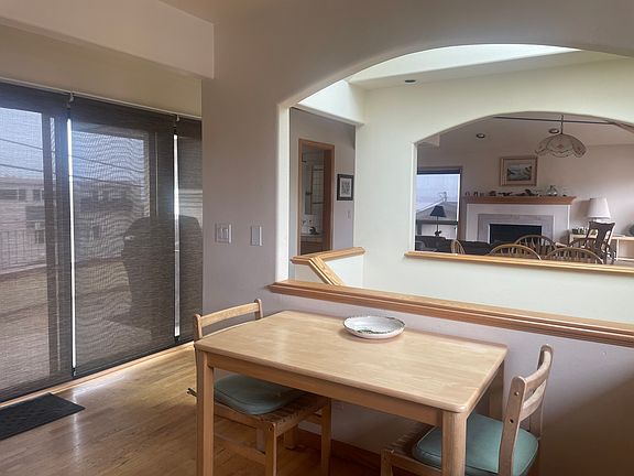 Deck behind glass doors and kitchen table. Stairs with skylight above and ding/living beyond.