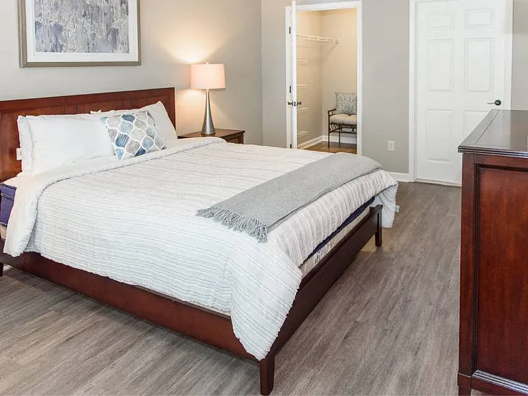 Spacious bedroom with plank flooring and view into walk-in closet (and door to ensuite bathroom)