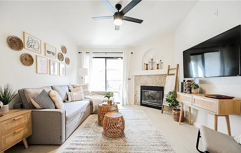 Spacious living area with a sectional, ceiling fan, fireplace, and large sliding doors opening to a balcony for added light.