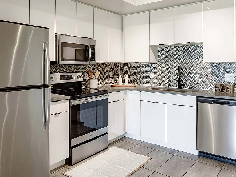 Griffis Pompano Beach apartment kitchen with quartz countertops and stainless steel appliances.
