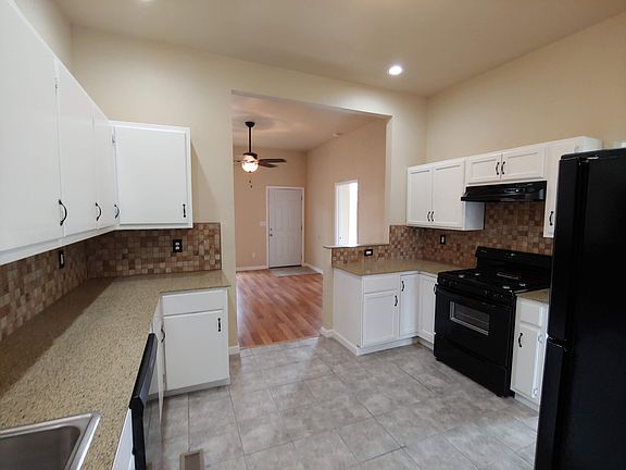 Kitchen is open to living and sunroom. With tile flooring, granite countertops. Refrigerator, range and dishwasher