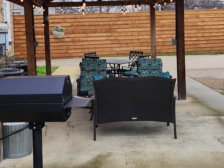 Back patio, with fans, string lights, seating and grill.