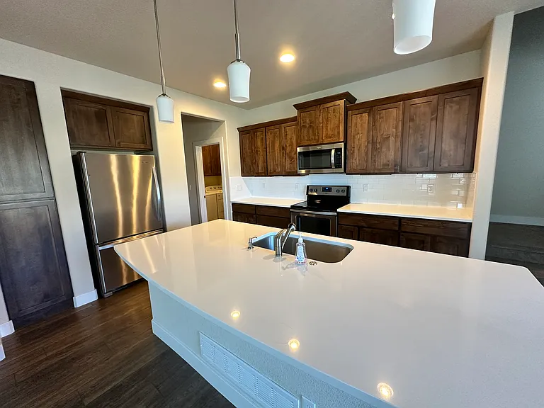 Quartz kitchen island with stainless steel sink and garbage disposal.