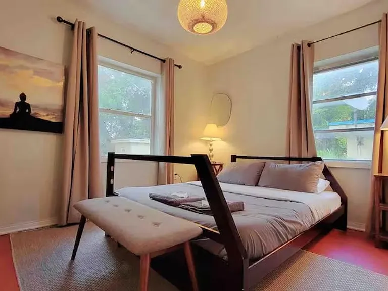 Furnished bedroom featuring a full bed, bench seating, and two windows with curtains for natural light and airflow.
