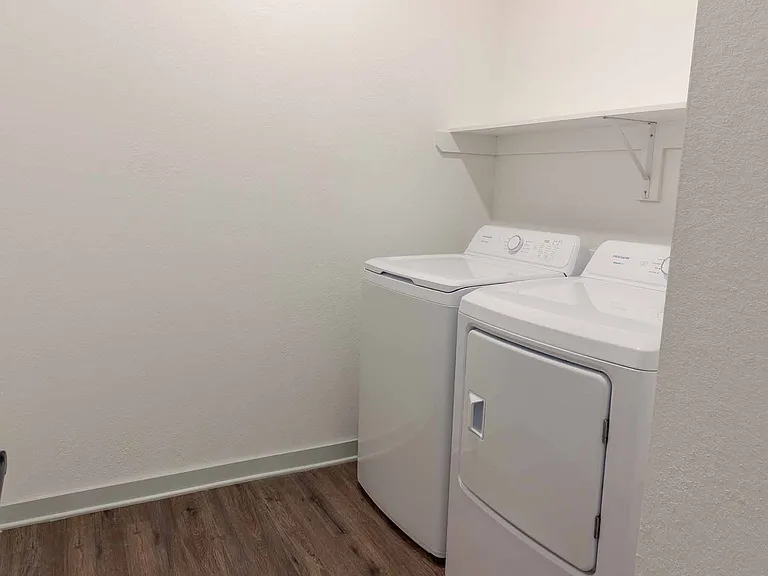 Dedicated laundry room with a full-size side-by-side washer and dryer plus an overhead storage shelf. Dedicated laundry room with a full-size side-by-side washer and dryer plus an overhead storage shelf.