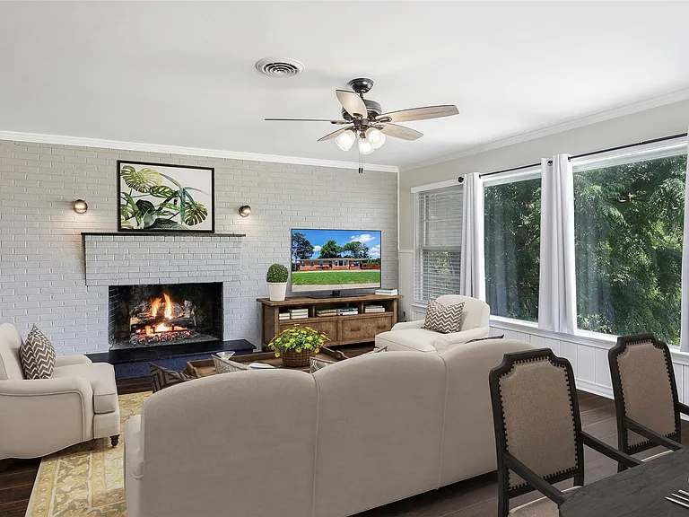 Virtually staged family room with plenty of natural light, ceiling fan, a fireplace, and dark wood-type flooring