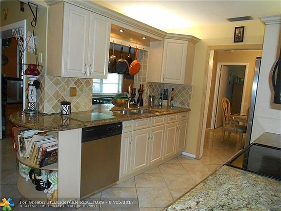 OTHER VIEW OF KITCHEN SHOWING GRANITE COUNTERS AND PASS THRU WINDOW.NOTICE TILE ON DIAGIONAL