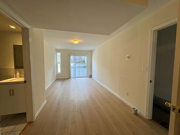 View from kitchen to living and dining room combo. new flooring . Left is bathroom and right is the front entrance . Sliding door to backyard