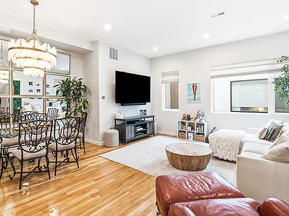 Open-concept living area with hardwood floors and modern finishes. Wall mirror decor included.