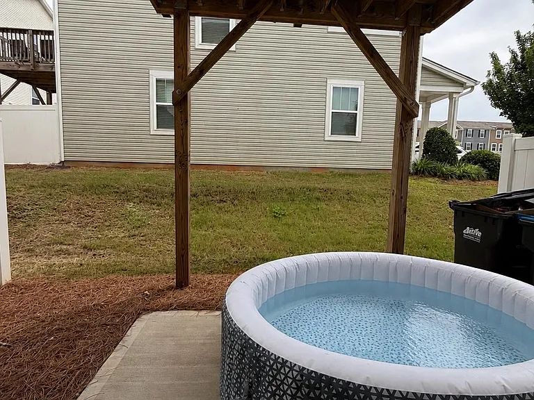 Covered backyard patio offers a concrete pad for outdoor seating, with a grassy yard and privacy fencing.