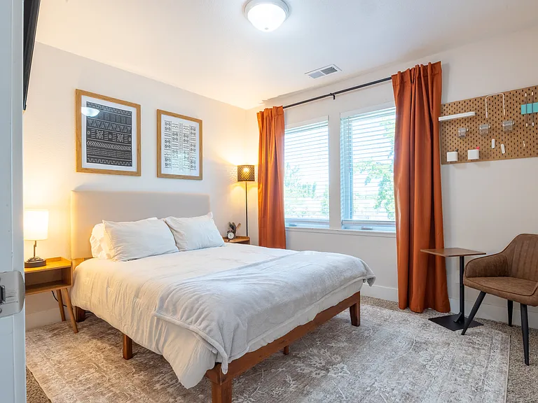 Guest Bedroom w/ mounted TV, queen size bed with memory foam, and blackout curtains