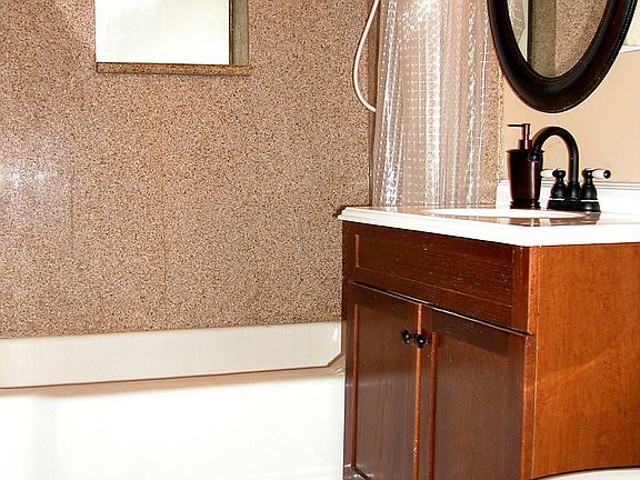 slab granite tub suround in bathroom with new vanity and mirror and tile floor