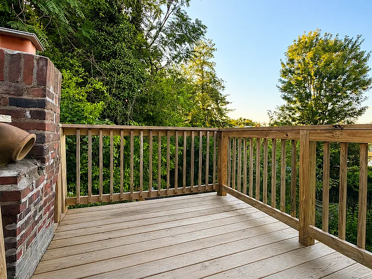 Private balcony with wood decking, secure railings, and peaceful views of surrounding trees _ a great spot for morning coffee or relaxing outdoors.