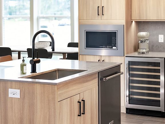 Signature Collection kitchen with stainless steel appliances (wine fridge included), quartz countertops, quartz tile backsplash, oak cabinetry, and hard-surface flooring