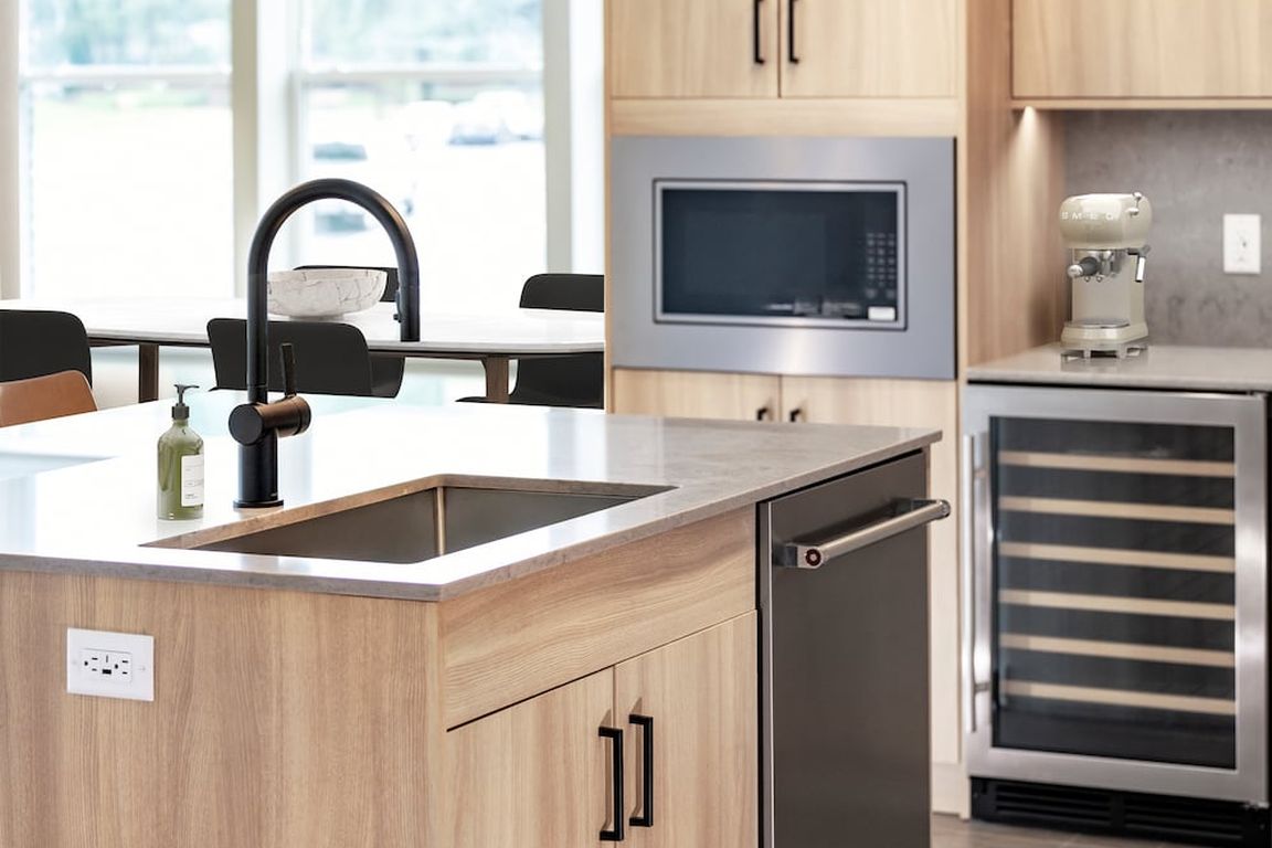 Signature Collection kitchen with stainless steel appliances (wine fridge included), quartz countertops, quartz tile backsplash, oak cabinetry, and hard-surface flooring