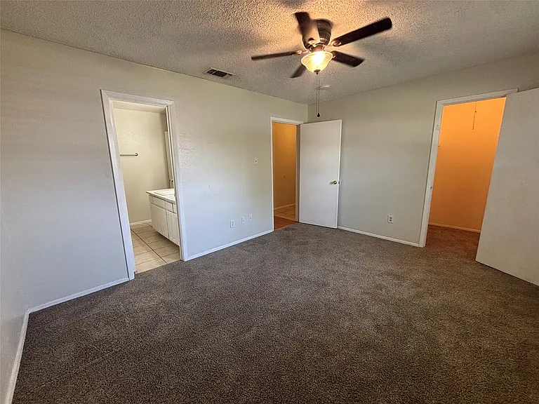 Spacious room featuring neutral-toned walls, brown carpeting, and a ceiling fan with integrated lighting