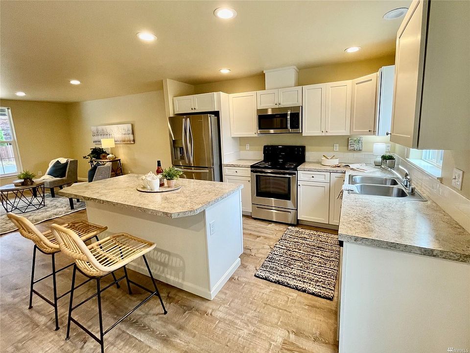 Charming kitchen with white cabinets and stainless appliances. Ample island and dining area.