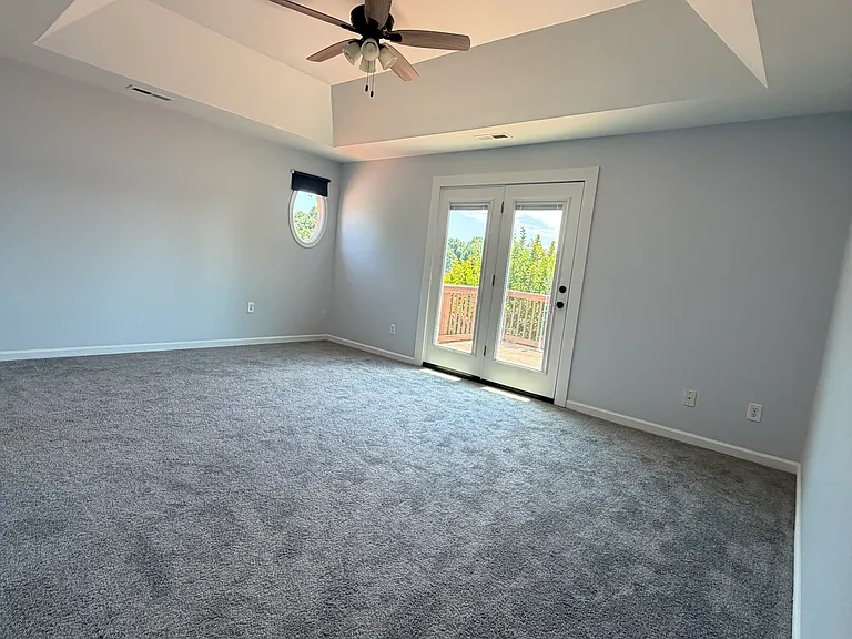 Primary bedroom on the second floor with direct access to a private deck and unobstructed water views_wake up to sunrise over the lake and step outside for morning coffee without leaving your suite.