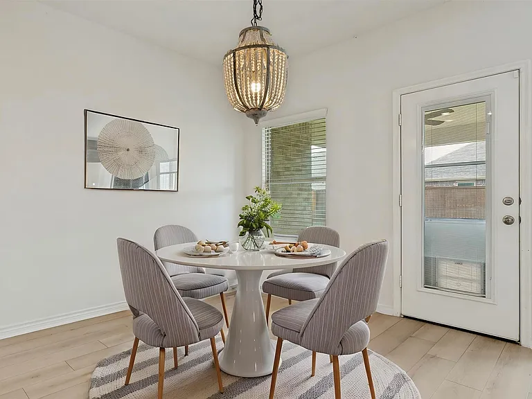 Eat-in dining space featuring wood-finish flooring, a contemporary beaded chandelier, a window with blinds, and a rear door with integrated blinds