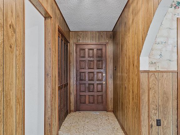 Foyer entryway featuring tiled flooring, a paneled entry door, and a built-in louvered closet
